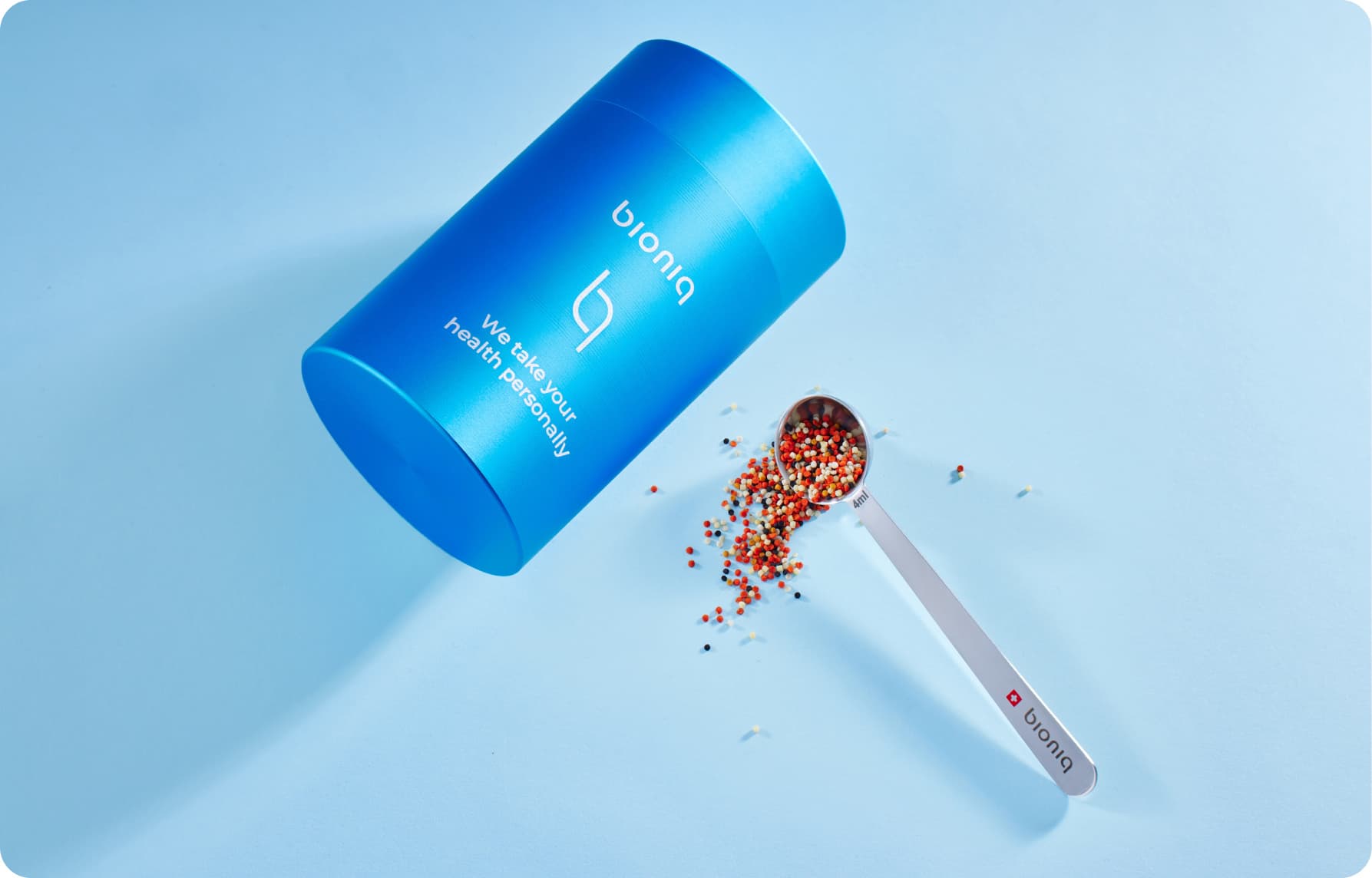 Hand holding a spoonful of Bioniq GO granules over the bottle